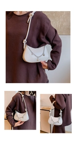 Detail of white half-moon bag featuring silver star charms and a knotted rope shoulder strap