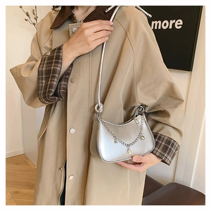Detail of silver metallic crescent bag with star chain charm on a trench coat