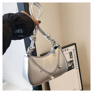 Detail of silver metallic crescent bag with knotted handle and decorative pearl chain