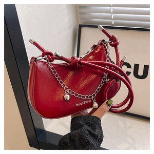 Detail of red glossy patent leather handbag with silver chain and heart pearl charms