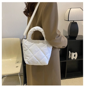 Detail of white quilted tote bag featuring plush padded handle and magnetic snap closure