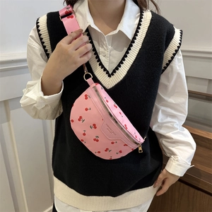Sac bandoulière rose avec imprimé cerise et sangle ajustable porté par un mannequin