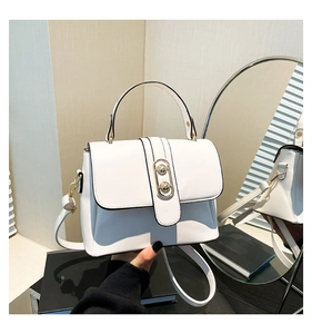 Detail of white leather handbag with golden oval metal clasp and twin beads accent