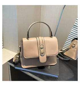 Detail of beige crossbody bag with gold oval buckle and detachable shoulder strap