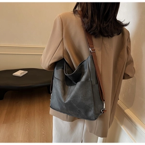 Detail view of large dark grey leather tote bag with wide brown shoulder strap