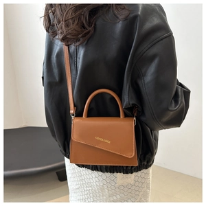 Rear view of woman wearing a brown leather handbag with adjustable strap and top handle
