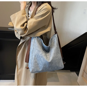 Detail of light blue felt tote bag featuring brown woven strap and silver metal hardware