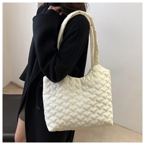 Detail of off-white quilted tote bag with heart-shaped padding and soft shoulder strap