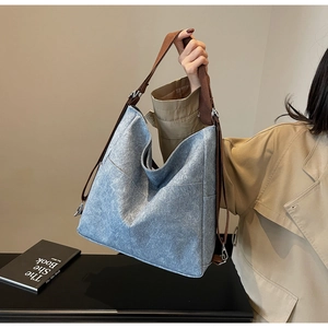 Detail of grey-blue large tote bag featuring brown woven handles and functional side pocket