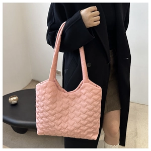 Detail of pink puffy tote bag with heart quilting and glossy nylon texture on shoulder strap