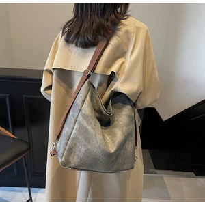 Close-up of a large tote bag with distressed gray leather texture and brown strap detail