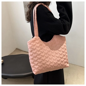 Detailed side view of pink quilted heart-patterned tote bag on model shoulder