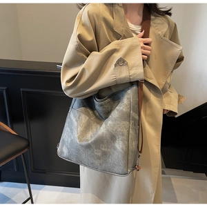 Detailed view of a smoke grey leather tote bag with brown adjustable straps on a model