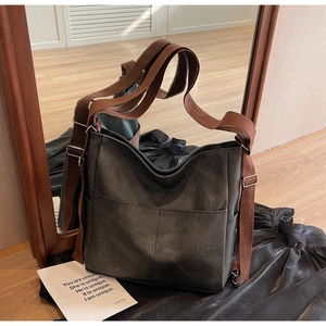 Detail of vintage green leather tote bag with adjustable brown canvas shoulder straps