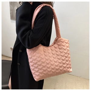 Detail of pink heart-quilted tote bag featuring glossy fabric and puffy texture