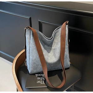 Blue-grey canvas tote bag detail on chair showing durable straps and side pocket