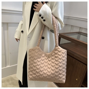 Pale pink quilted tote bag with heart patterns shown on a model's shoulder