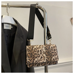 Detail of leopard print crossbody bag with wide black strap and gold metal hardware