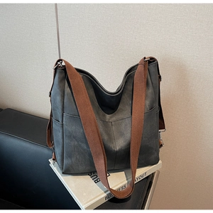Detail of dark grey tote bag featuring a matte finish and wide brown canvas shoulder strap