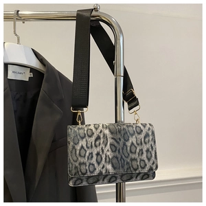 Detailed shot of leopard print crossbody bag with black strap hanging on a blazer