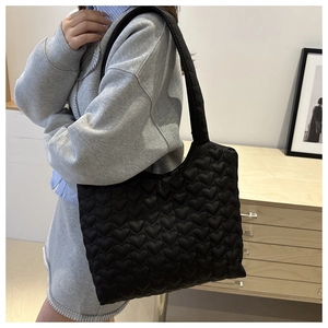 Close-up of black heart-quilted nylon tote bag with 3D padded texture and large capacity