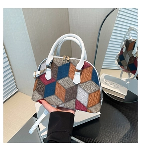 Détail du sac coquillage avec patchwork géométrique contrasté et poignées blanches élégantes