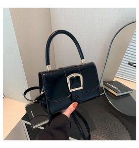 Detail of elegant black glossy mini square bag with golden U-shaped metal buckle buckle