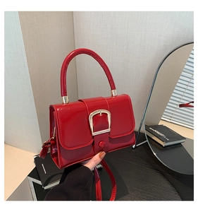 Detail of red patent leather square bag with gold metal buckle and sturdy handle