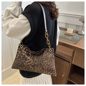 Detail of leopard print tote bag featuring an acrylic chain link and brown strap