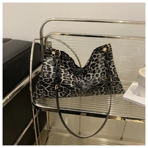 Detalle de bolso tote de leopardo con cadena negra gruesa y herrajes de aro dorado