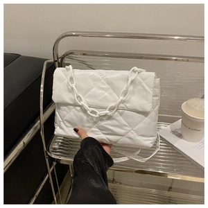 Détail du sac matelassé blanc avec texture en losanges et bandoulière en chaîne épaisse