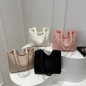 Quilted heart pattern tote bags in four colors shown on a white display stand