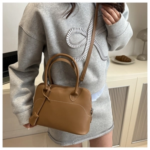 Detailed close-up of brown matte leather shell bag with white decorative stitching
