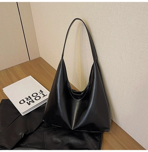 Détail macro du sac cabas hobo en similicuir noir posé sur une surface en bois