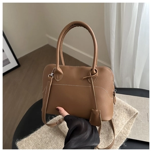 Detail of vintage brown shell bag showing delicate white stitching and leather texture