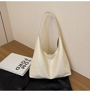 Détail du sac hobo crème minimaliste avec texture cuir grainé et bandoulière sans couture
