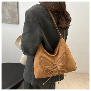 Detail of brown suede hobo bag with leather butterfly patch and side lace-up details