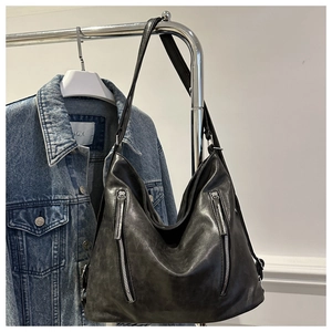 Detail of vintage black PU hobo bag featuring decorative metal zippers and leather texture