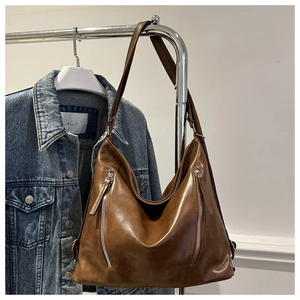 Detailed close-up of brown leather hobo bag featuring twin vertical zipper accents