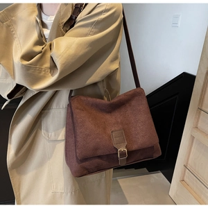 Detail of vintage brown suede crossbody bag with metal buckle strap on a model