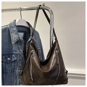 Detail of dark brown wax leather hobo bag with dual vertical zippers and adjustable strap