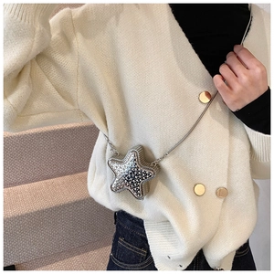 Close-up of star-shaped crossbody bag with rhinestones and metal chain on a knit cardigan