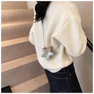 Mini star-shaped crossbody bag with silver sequins and metallic chain worn by model