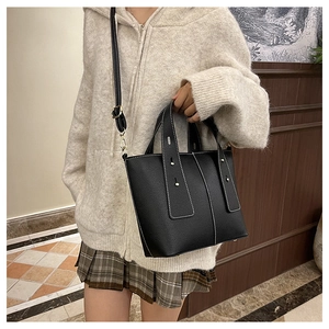 Détail du sac seau en cuir noir avec surpiqûres blanches contrastées et boucle dorée