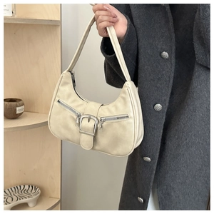 Detailansicht der cremefarbenen Ledertasche mit Metallreißverschlüssen und großer Silberschnalle