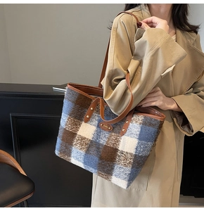 Macro detail of the woolen plaid tote bag with brown leather handles and metal hardware