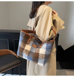 Close-up of winter plaid tote bag featuring blue and brown woven texture and leather straps