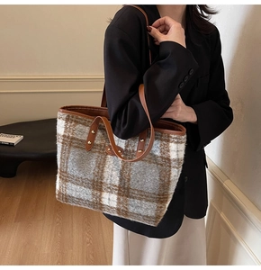 Detail of the oversized woolen plaid tote bag showing its rich texture and leather handle