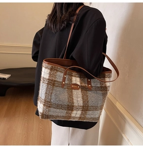 Detail of grey plaid wool tote bag with brown leather handles and brand logo