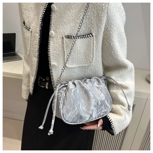 Detail of silver metallic cloud bag with drawstring closure and metal chain strap